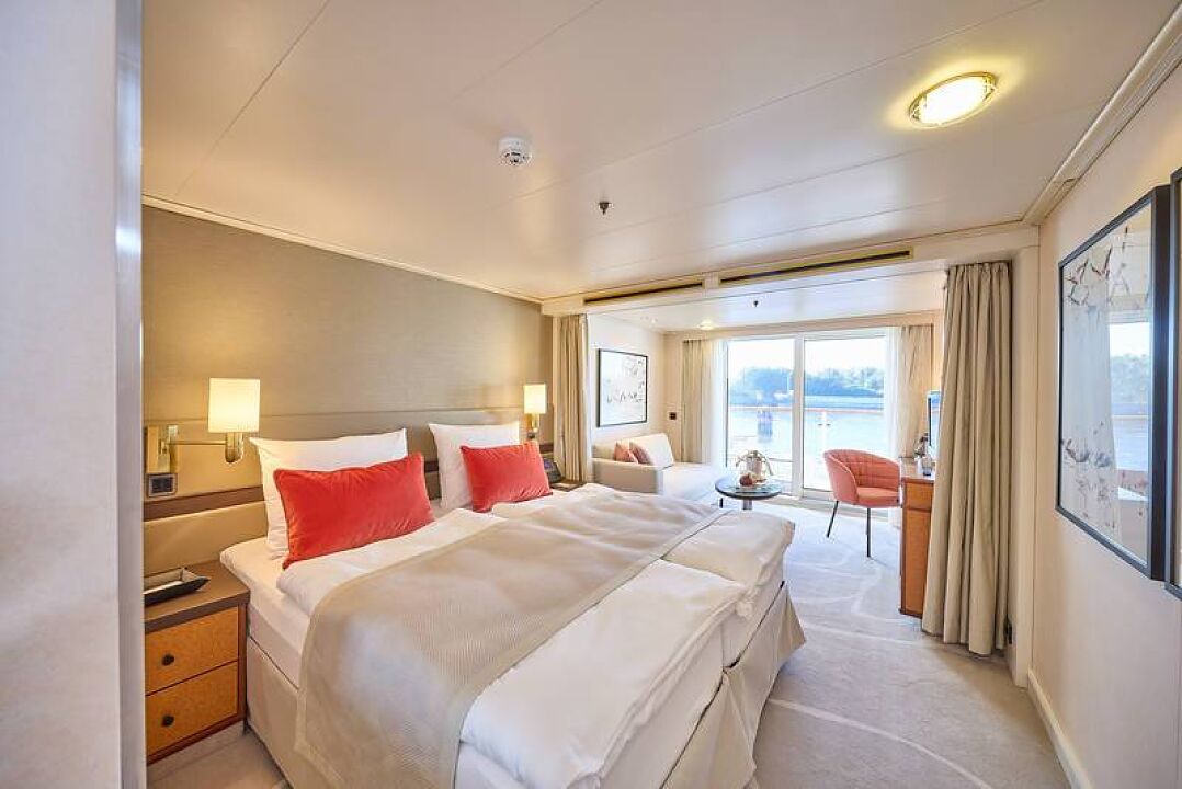 Warme Korallentöne, elegante Möbel sowie ein stilvoller Teppich in hellem Beige zieren 132 Suiten, © Hapag-Lloyd Cruises/Wyrwa